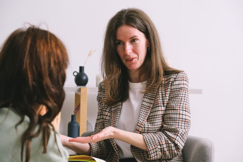 Positive adult female psychologist in smart casual outfit smiling while talking.